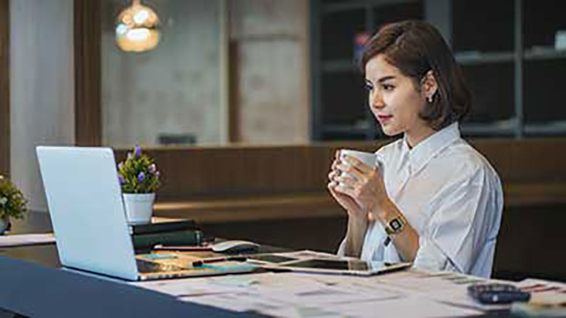 woman-holding-cup-looking-at-laptop-800x450